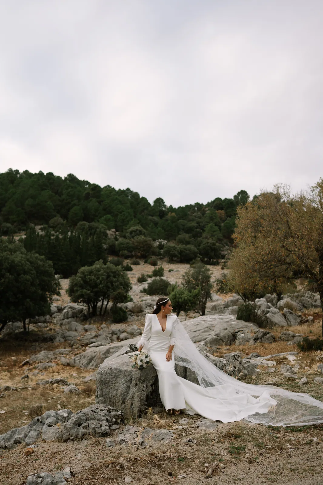 Novia sentada en las rocas con el velo