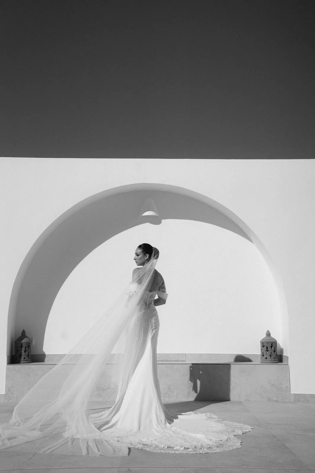 Novia bajo un arco blanco con el velo al viento